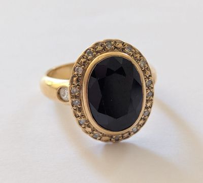 un gros plan sur une bague en or sertie d'une pierre noire entourée de diamants blancs