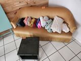 un canapé sur lequel sont posés beaucoup de vêtements