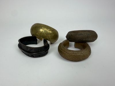 trois bracelets en bois et en laiton posés sur une surface blanche