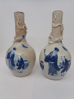 une paire de vases bleus et blancs ornés de personnages sur fond blanc