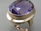 un gros plan d'une bague en or sertie d'une grosse pierre violette
