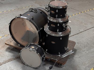a black drum set sitting on the ground next to a pair of drums