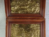 two framed gold leaf paintings on a white wall