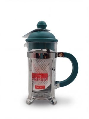 La cafetière à piston est en acier inoxydable et possède un couvercle vert.