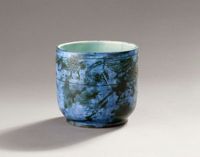 a blue cup sitting on a table with a shadow on the ground