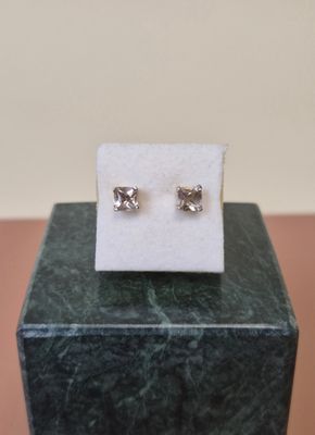 a pair of earrings sitting on top of a marble block
