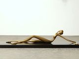 a gold statue of a woman laying on a black base