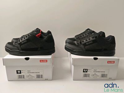 deux paires de baskets noires posées sur des cartons, sur une surface blanche