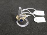 une bague sertie d'une pierre bleue, posée sur une table