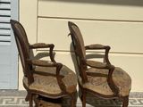 two wooden chairs sitting next to each other on the sidewalk