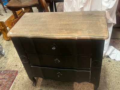 une commode noire surmontée de trois tiroirs