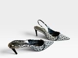 une paire de chaussures en peau de serpent noire et blanche posées sur une surface blanche