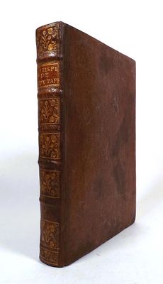 an old brown book sitting on top of a table next to a white wall