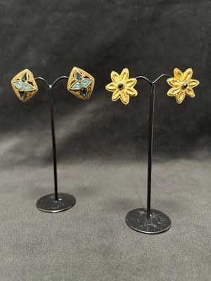 a pair of gold and turquoise flower earrings on a black stand