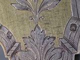 a close up of a silver clock with a floral design on it