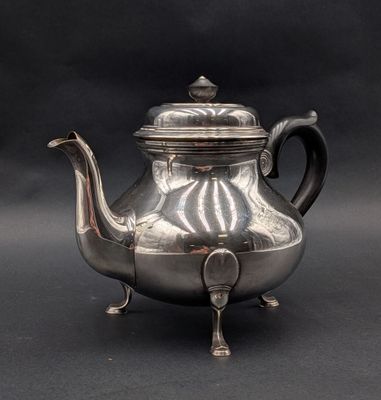 une théière ancienne en argent avec son couvercle, sur fond noir