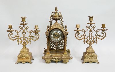 trois bougeoirs dorés et une horloge sur fond blanc