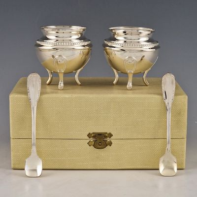 deux bols et cuillères en argent posés sur une boîte