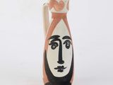 a vase with a face painted on it on a white surface