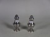two silver salt and pepper shakers on a white surface
