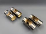 a set of four stainless steel pipe holders on a gray surface