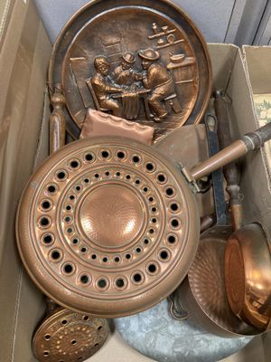 une boîte contenant tout un tas de casseroles et de poêles en cuivre