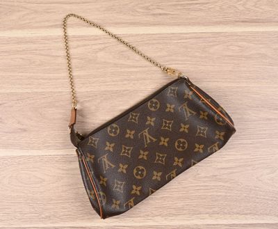 un sac de poignet Louis Vuitton posé sur un parquet