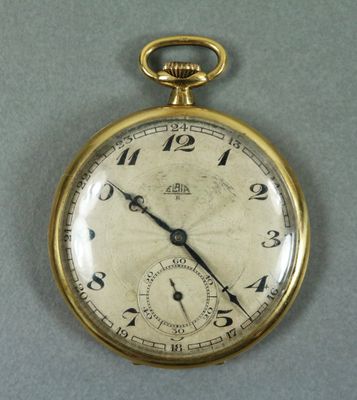 un gros plan d'une montre de poche en or posée sur une surface grise