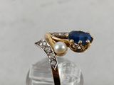 a close up of a gold ring with a blue stone and a pearl