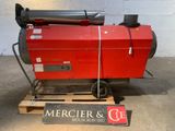 une machine rouge posée sur une palette dans un entrepôt