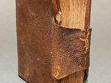 an old brown book sitting on top of a table next to a gray wall