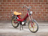 a small red motorcycle parked in front of a brick wall