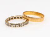 two gold rings with diamonds on them on a white surface