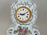 une horloge blanche ornée de fleurs roses, posée sur un socle