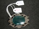 a picture of a necklace with a green stone on it