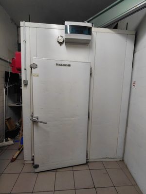 un réfrigérateur blanc dans une petite pièce, avec un micro-ondes posé dessus