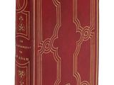 un vieux livre rouge aux tranches dorées, avec un motif décoratif sur la couverture