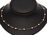 a necklace with pearls and gold chains on a black mannequin