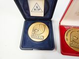 a gold medal sitting in a red box next to a gold medal