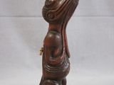 wooden statue of a woman with a hat on her head sitting on a stool