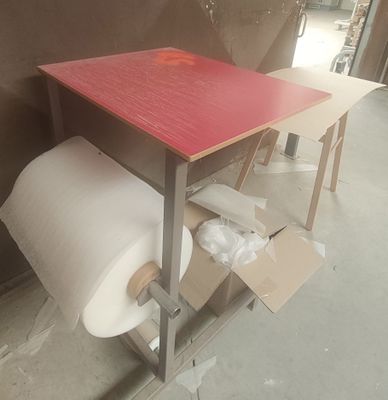 une table rouge sur laquelle est posé un rouleau de papier toilette