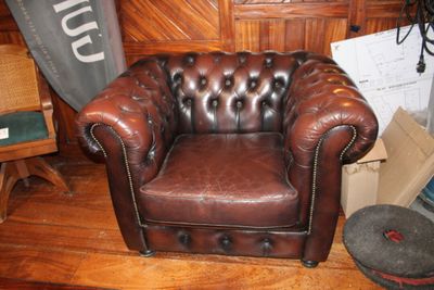 un fauteuil en cuir marron posé sur un parquet en bois massif