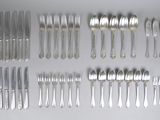 a lot of silver spoons and forks laid out on a table