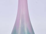 un vase bleu et rose posé sur une surface blanche
