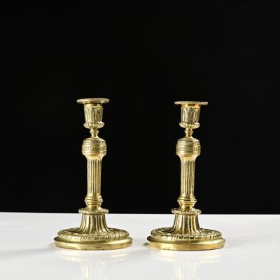 une paire de bougeoirs en laiton posés sur une table blanche