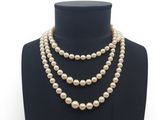 un collier de perles blanches sur un mannequin avec un fermoir en or