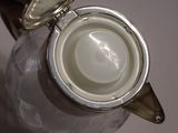 a white tea pot with a silver lid on a table