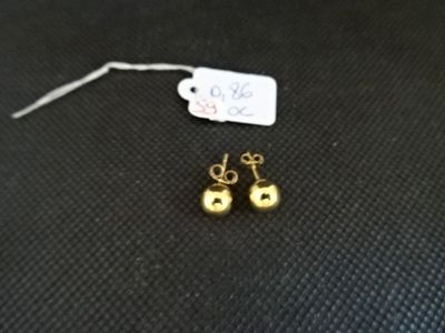 un gros plan sur une paire de boucles d'oreilles en or posées sur une surface noire