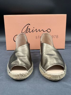 une photo d'une paire d'espadrilles dorées avec une boîte en arrière-plan