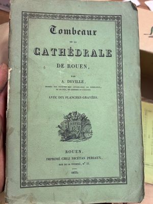une personne tient un livre à la main devant une pile de livres